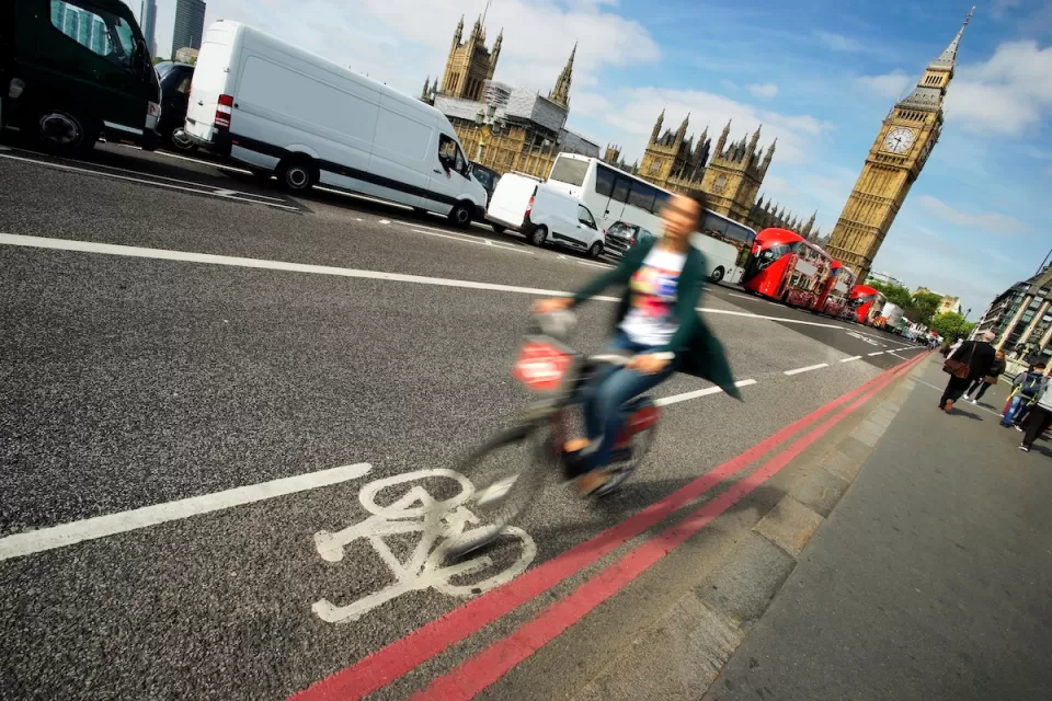 Blurry person in bike riding quickly in bike lane with Big Ben in background in London, UK.